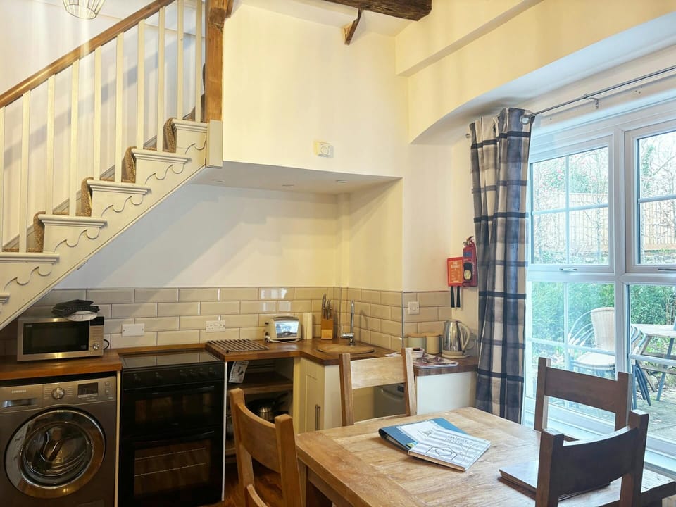 Wooden table and chairs beside kitchen units under staircase