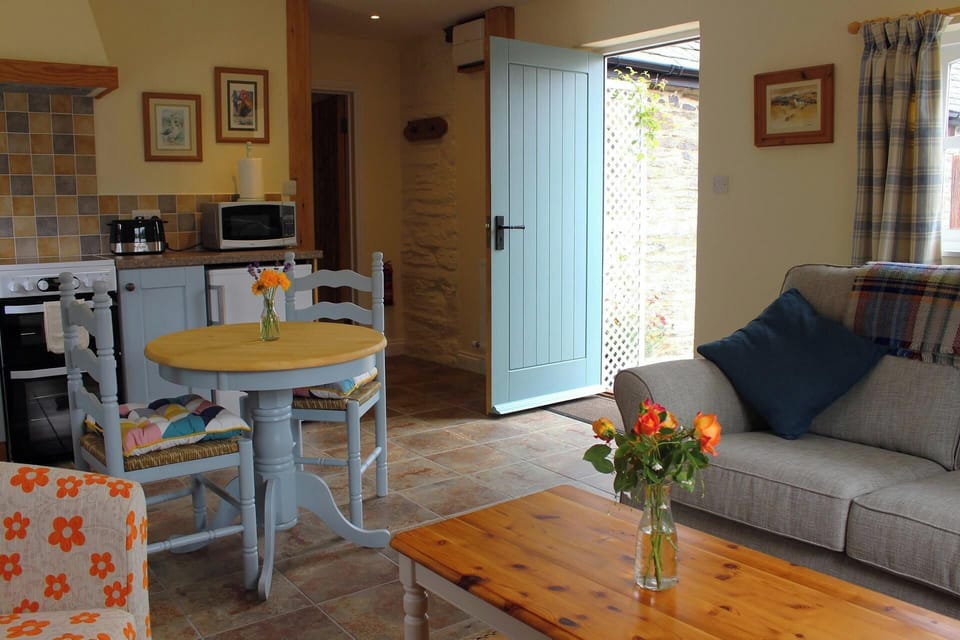 Table and chairs, coffee table, sofa, door to garden and flowers in a vase