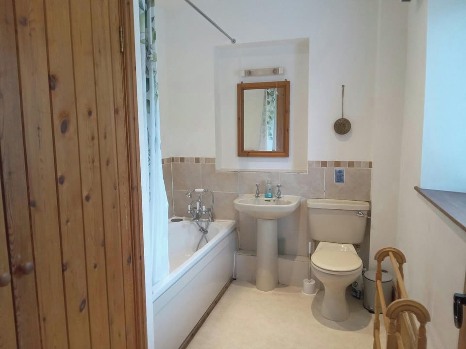 White bathroom with bath and shower curtain, sink and toilet