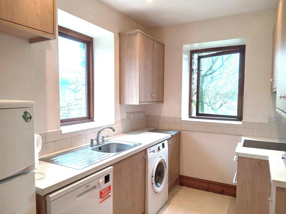 Fitted kitchen with sink, dishwasher, washing machine and two windows