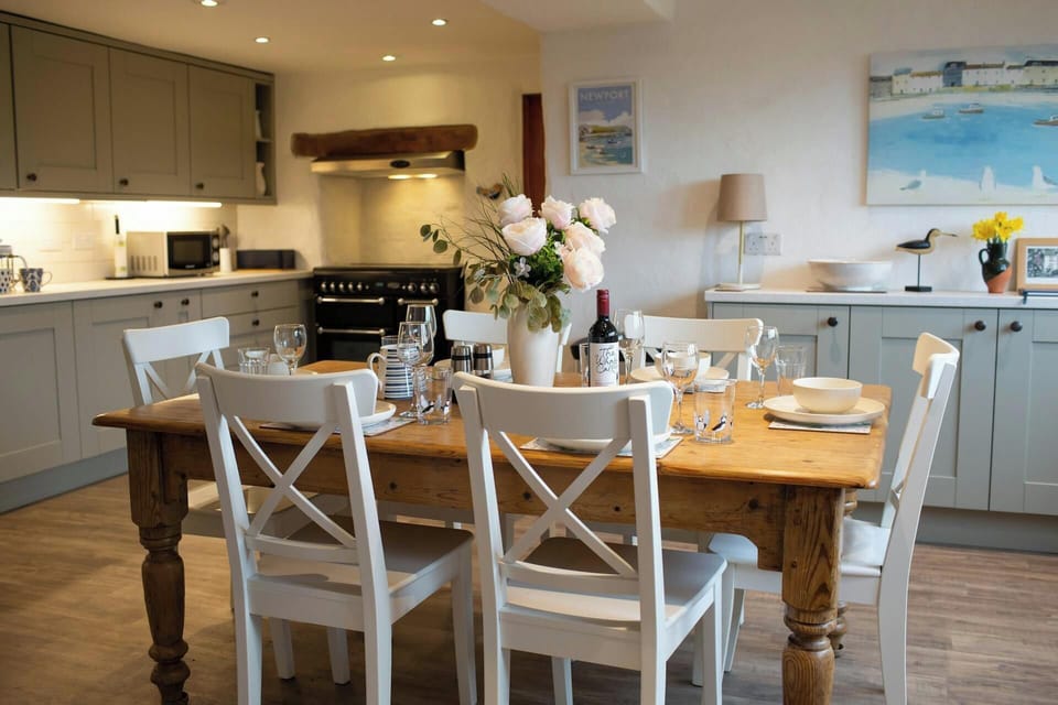 dining table to seat 6 laid for dinner with wine and flowers with kitchen behind and sideboard