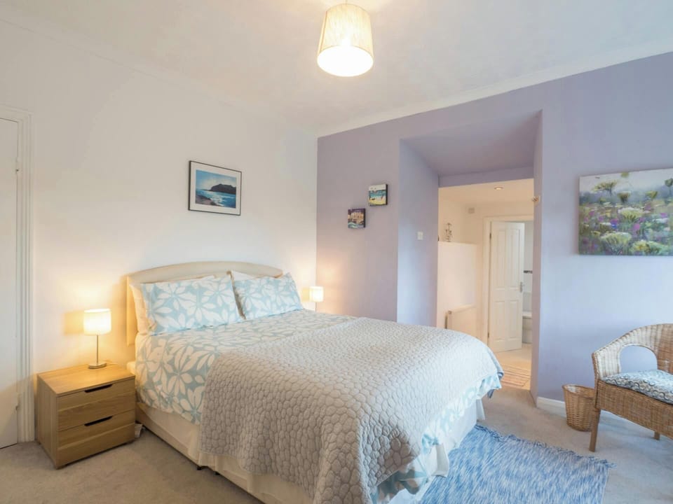 Master bedroom with king size bed, bedside drawers and lamps, armchair, ensuite