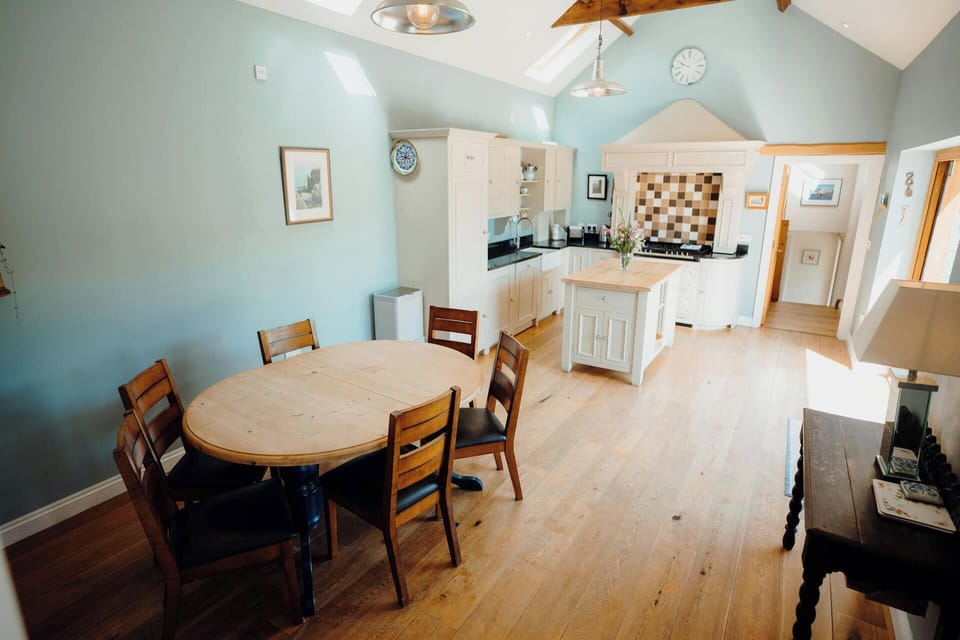 Open-plan kitchen and dining area with wooden table, chairs, and central island