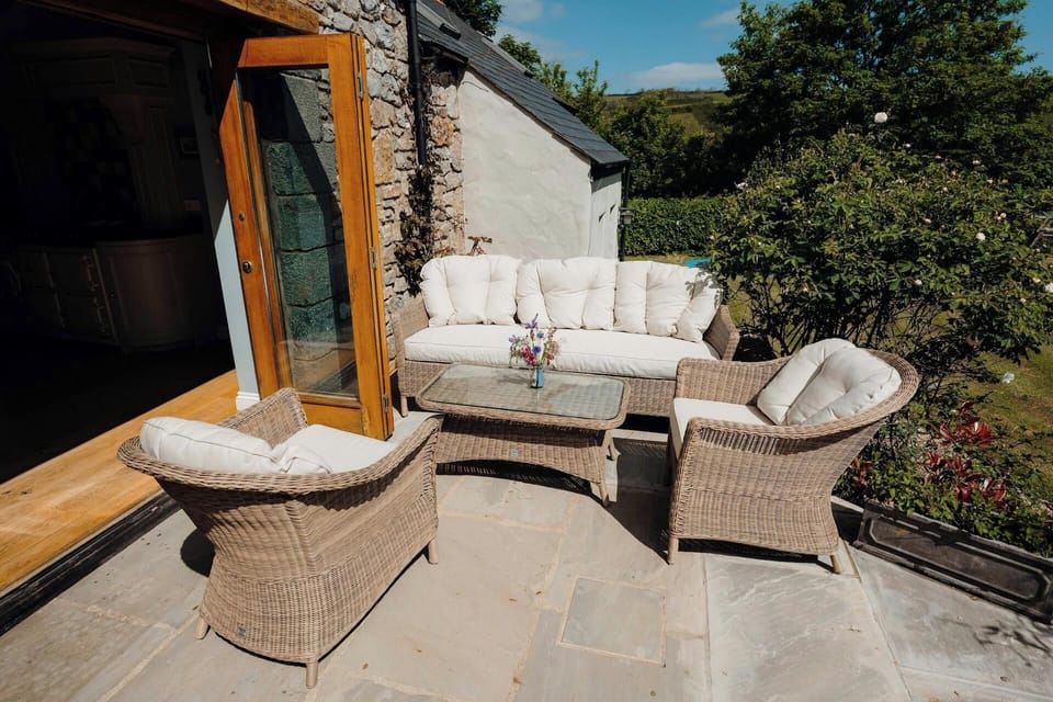 Wicker patio set with cushioned sofa and chairs beside an open wooden door
