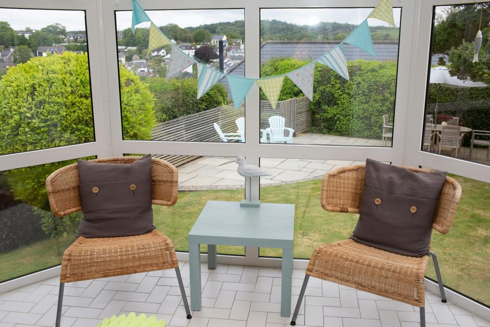 Conservatory with two chairs, coffee table, view of garden and patio