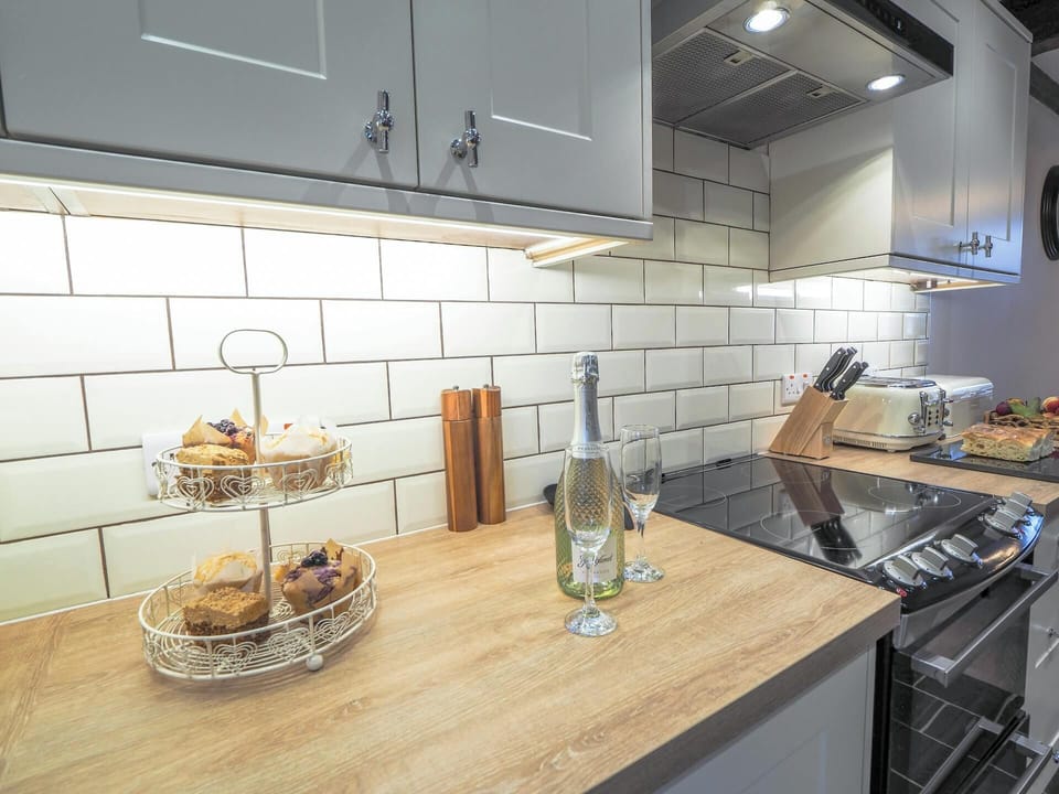 Wooden work surface with a bottle of wine and glasses. Electric cooker