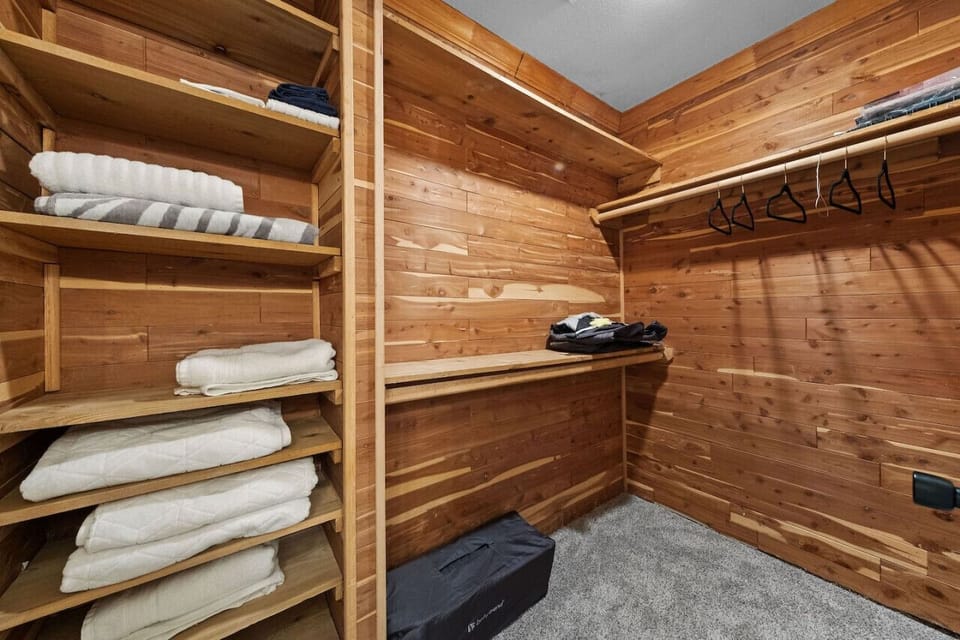 Spacious cedar-lined walk-in closet with built-in shelving, ample storage space, and cozy carpet flooring.