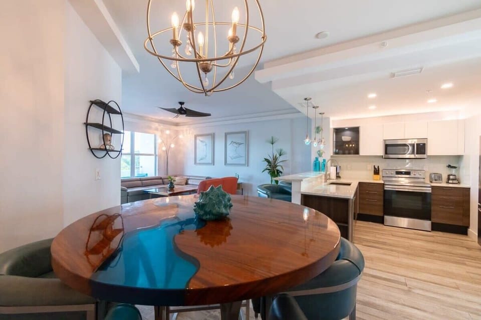 Modern open-concept kitchen and dining area with a unique resin wood table and stylish lighting.