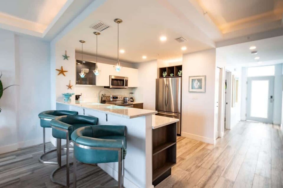 Modern kitchen with marble countertops and teal bar stools