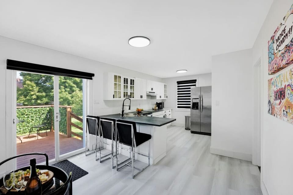 Spacious open-plan kitchen with modern appliances, a large island with bar seating, and direct access to a patio with outdoor dining. Enjoy natural light and seamless indoor-outdoor living. Perfect for entertaining! Book your stay now