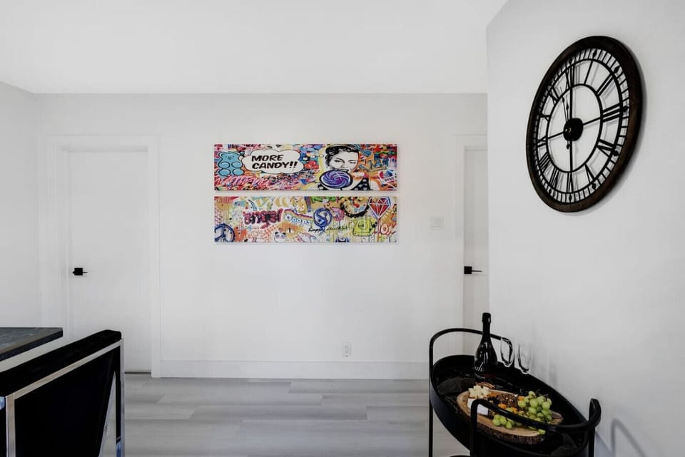 Charming space featuring vibrant wall art, a unique clock, and a stylish serving cart with delicious food. Perfect for a cozy meal or an artistic touch to your stay. Experience comfort & style! Book your memorable getaway.