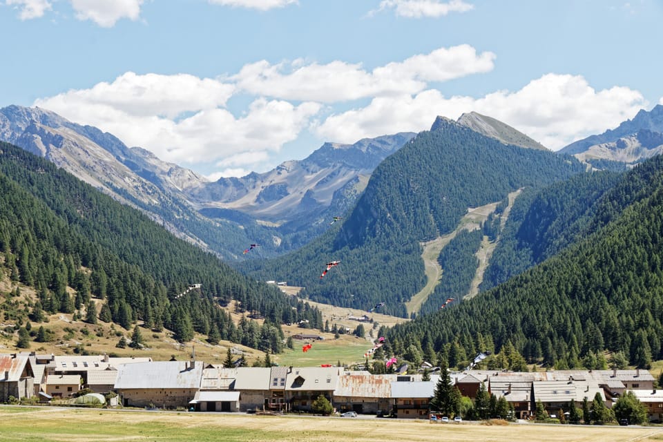 Paragliders drift over the forested valley below the residence, with the Bergers district just beyond the trees