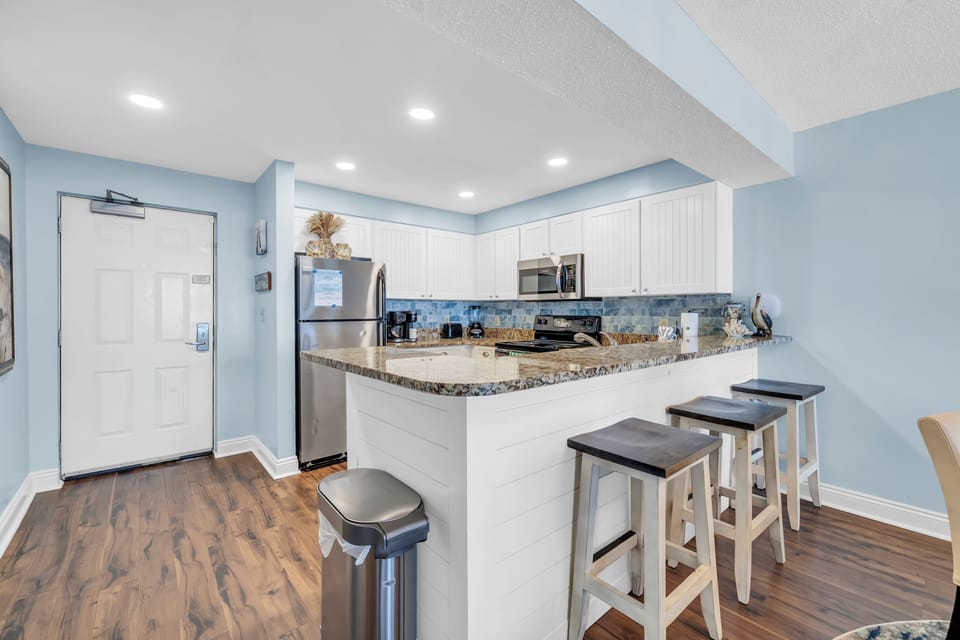 Your fully equipped kitchen features granite countertops, stainless steel appliances, and a breakfast bar where you can enjoy morning coffee.