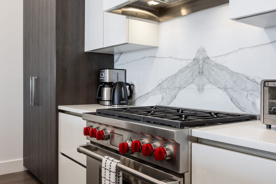 - Stainless steel Wolf gas range with bold red knobs and oven  
- Coffee maker and kettle included for morning mountain brews  
- Modern kitchen setup ideal for preparing group meals