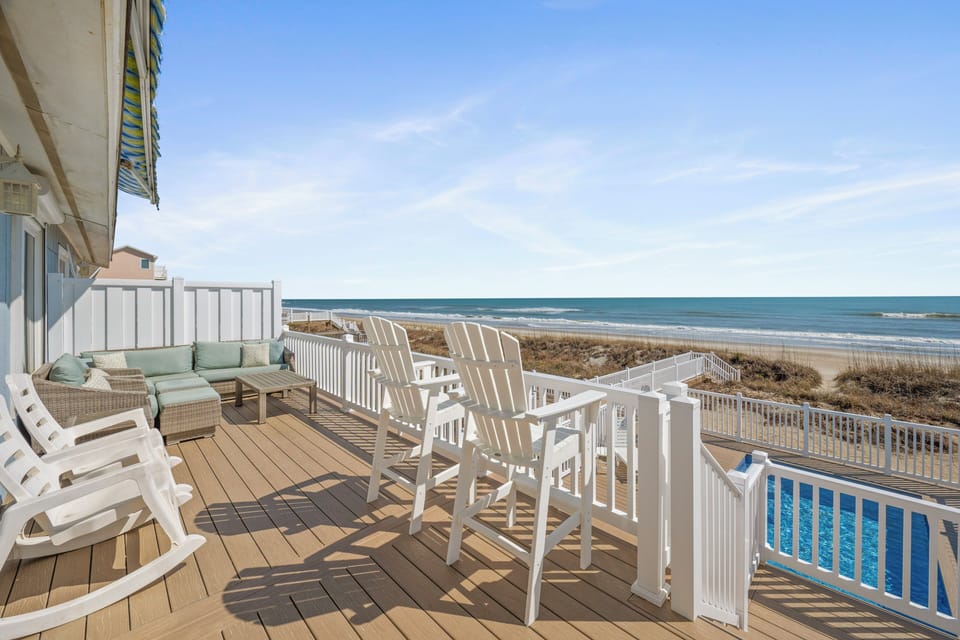 Step onto your private oceanfront deck where white Adirondack chairs await morning coffee rituals, complete with cozy seating and stunning sea views.