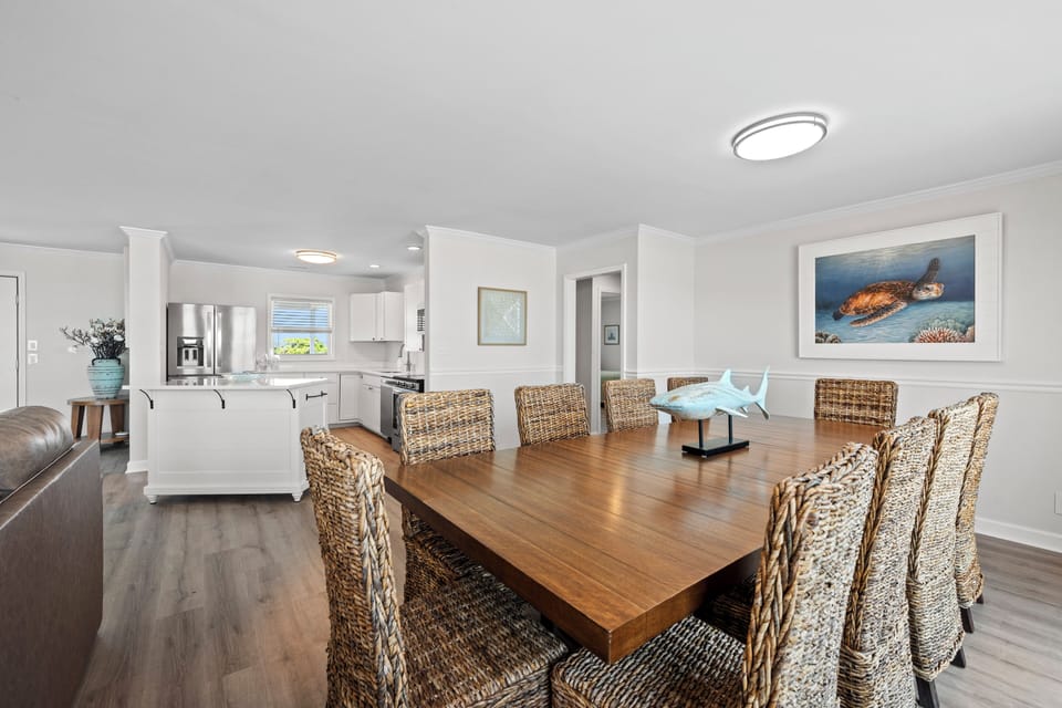 Gather around this spacious dining table where your group can share meals and stories, while the open-concept kitchen keeps everyone connected, creating a warm, communal heart for your stay.