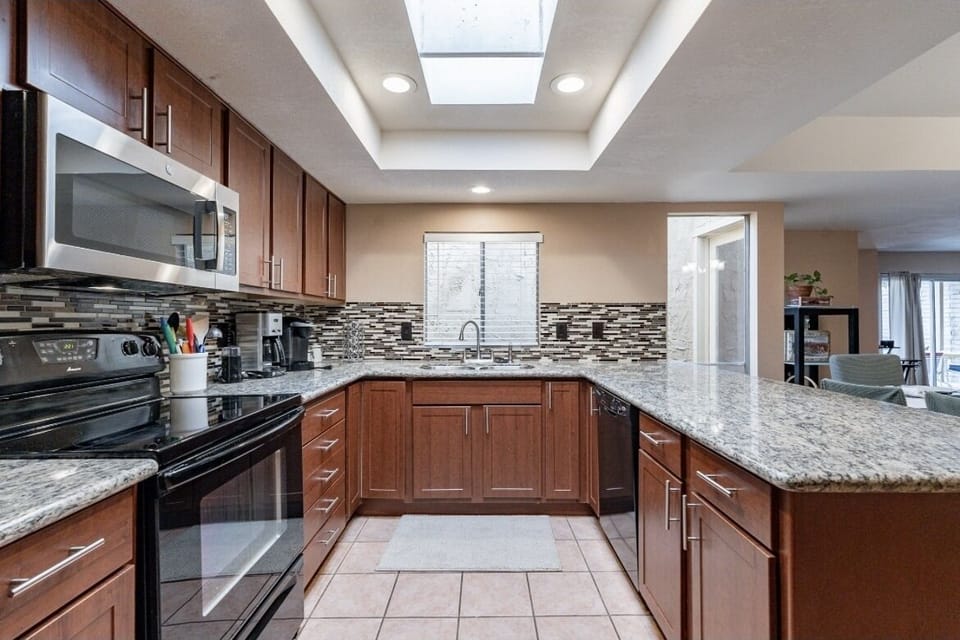 Modern kitchen features dishwasher, both drip and Keurig coffee maker.