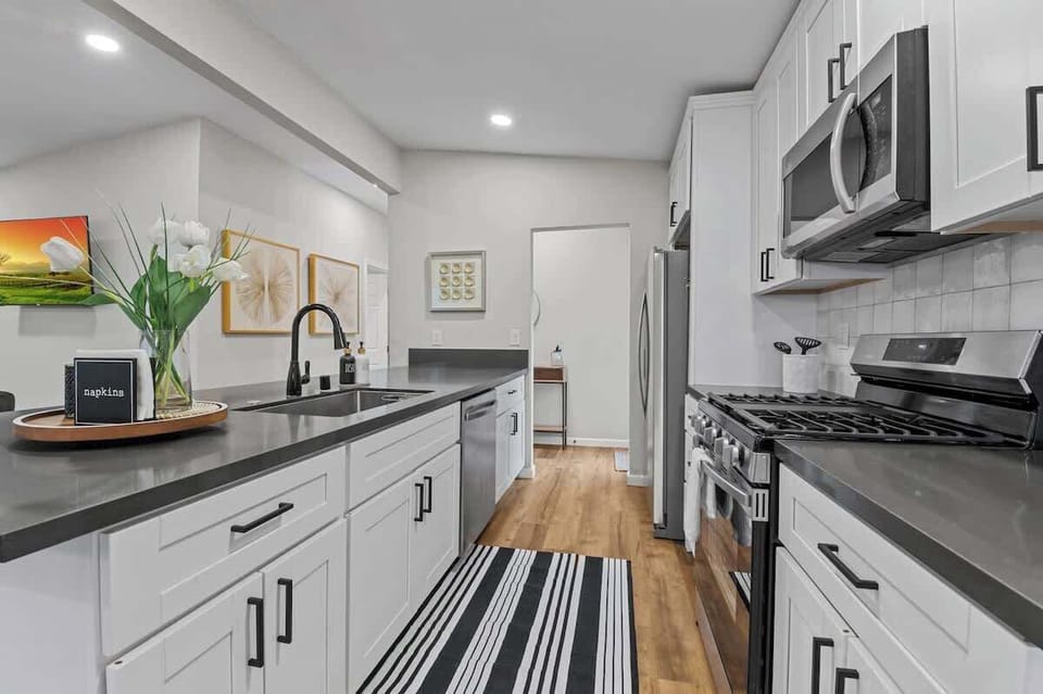Modern Kitchen with Sleek Black Countertops, White Cabinetry, Stainless Steel Appliances, Ample Space, Elegant Decor, and a Stylish Design Perfect for Cooking, Dining, and Entertaining Guests in Comfort.