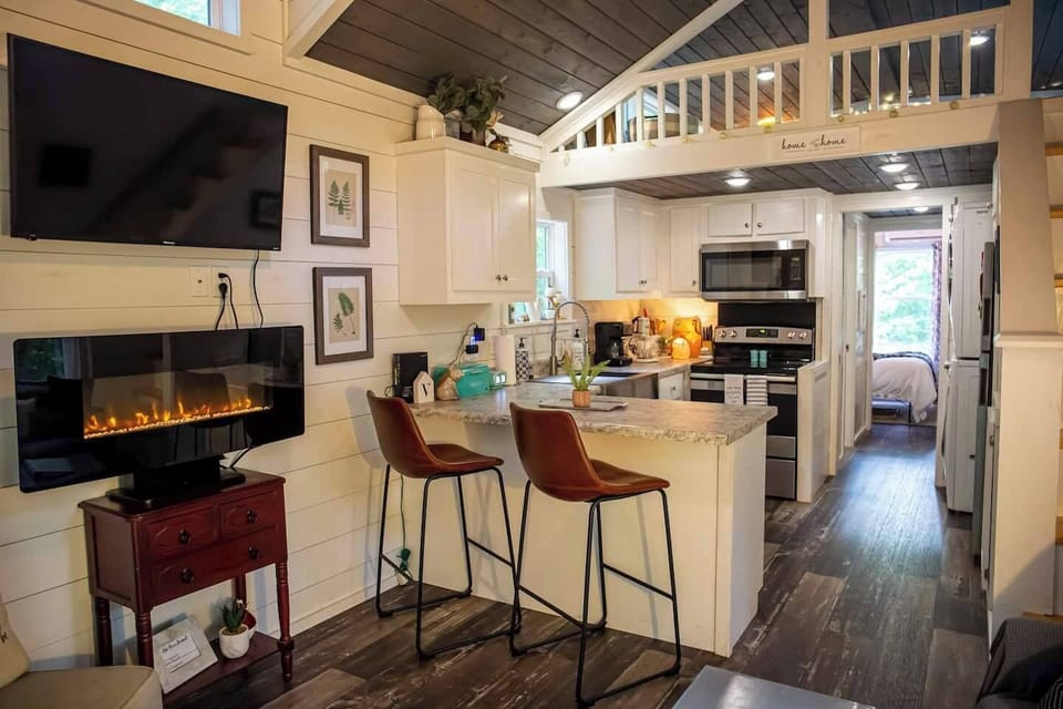 Cozy farmhouse-style tiny house with an electric fireplace and Wi-Fi—perfect for streaming or working from home with a change of scenery. Enjoy a fully equipped kitchen, a main-floor master bedroom, and comfy bunk beds.
