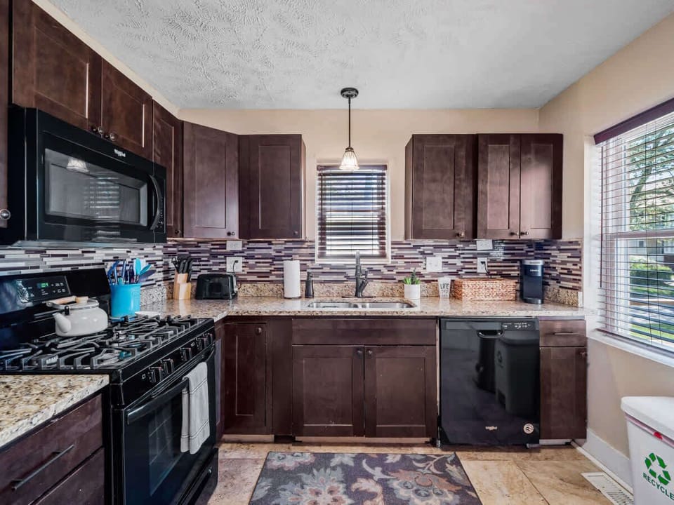 Modern kitchen w/ granite counters, rich wood cabinets & window views