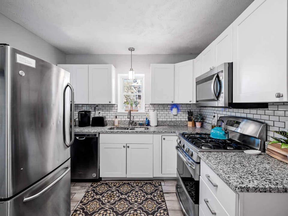 Bright kitchen w/ white cabinetry, stainless appliances & spacious counters