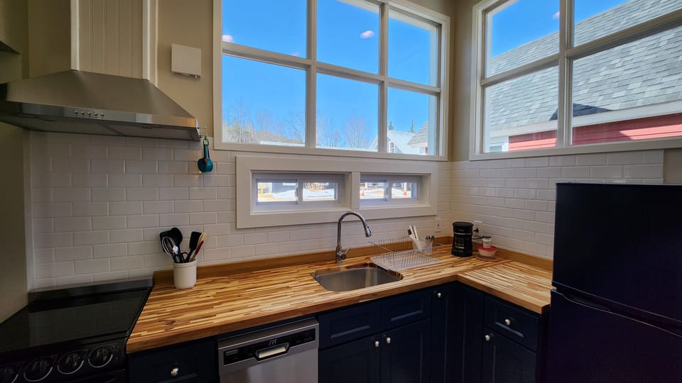 Kitchen equipped with an oven, dishwasher, fridge, and basic cooking utensils.