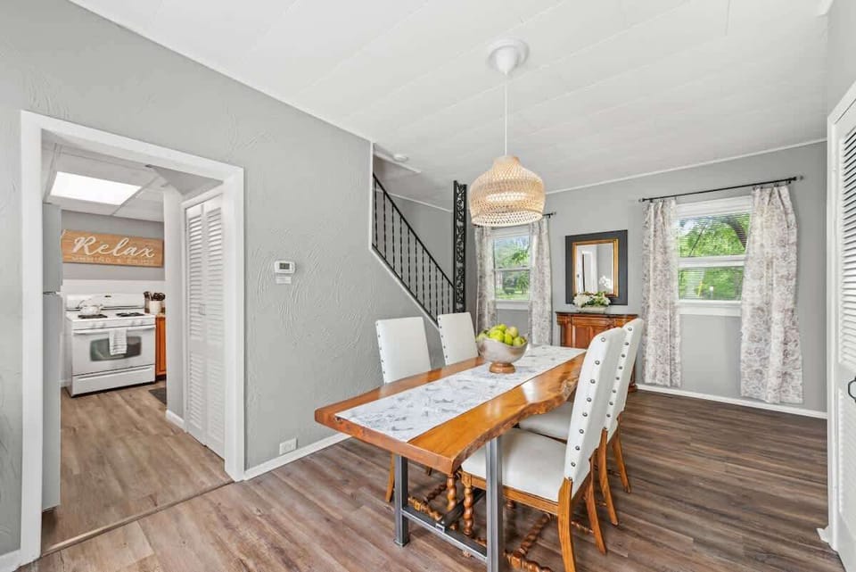 Bright dining area w/ long wood table, large windows & warm pendant lighting for shared meals
