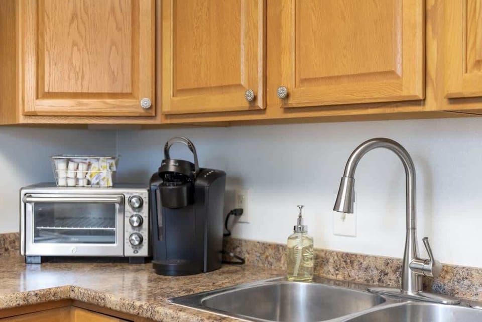 Kitchen counter w/ sink, coffee maker & warm wood cabinetry for easy morning routines