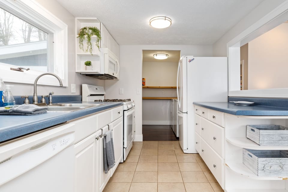 Bright galley kitchen w/ white cabinets, blue counters & plenty of prep space