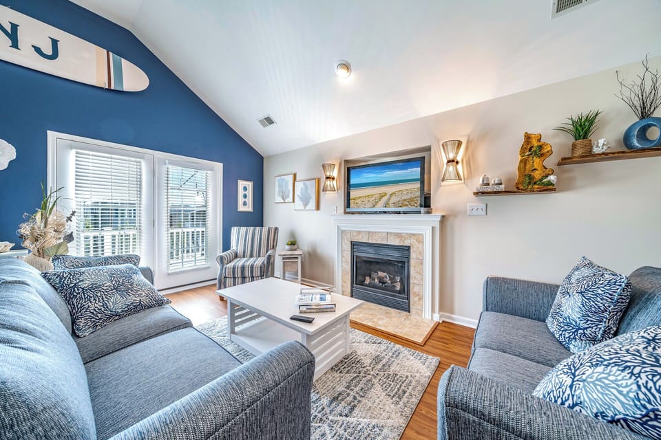 Coastal-themed living room with vaulted ceilings, fireplace, and smart TV