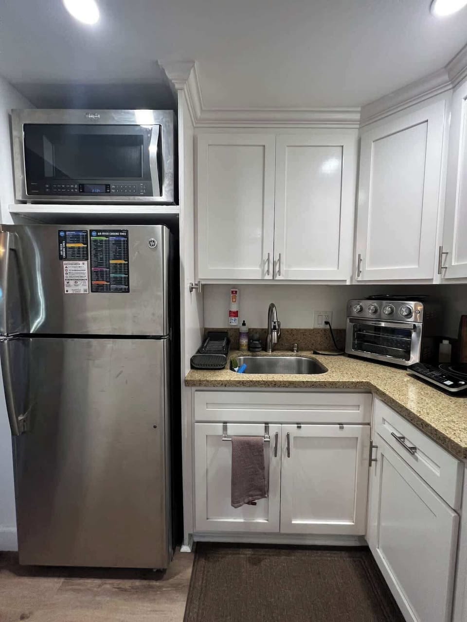 Kitchenette with full size fridge, microwave, sink, air fryer/toaster oven, and burner.