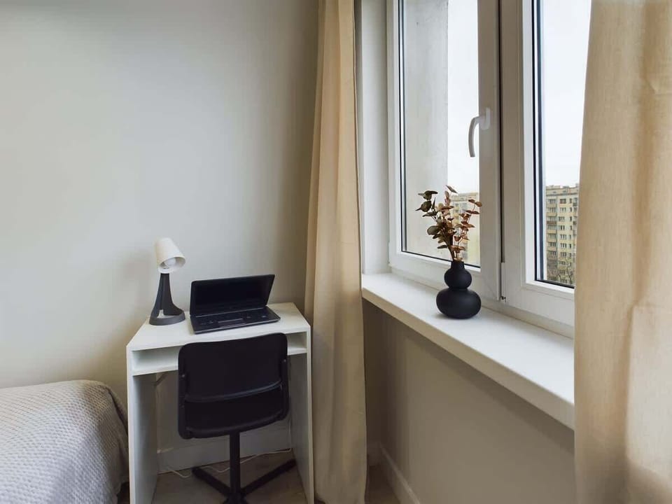 Desk with a laptop and a chair near a window. The room is well-lit and appears to be a workspace.
