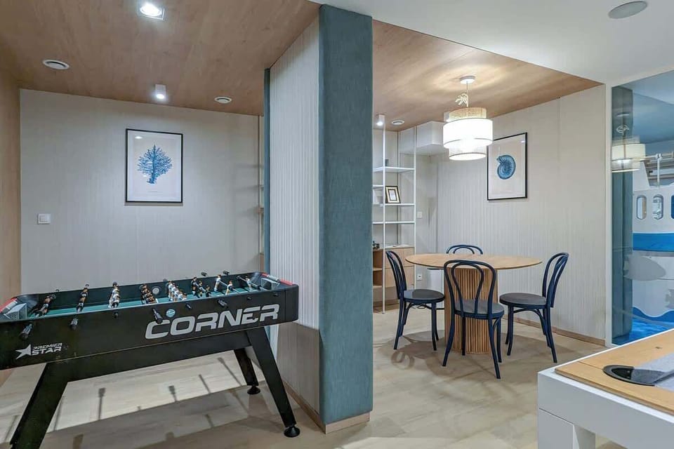 A hallway features a foosball table and a bookshelf, suggesting a recreational space.
