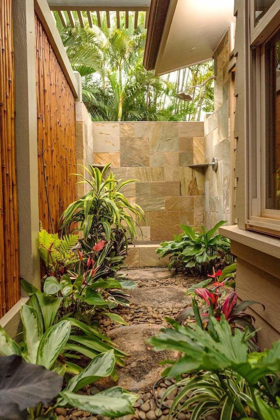 Rejuvenate in the private outdoor shower surrounded by vibrant tropical plants for a refreshing, unique experience.'
