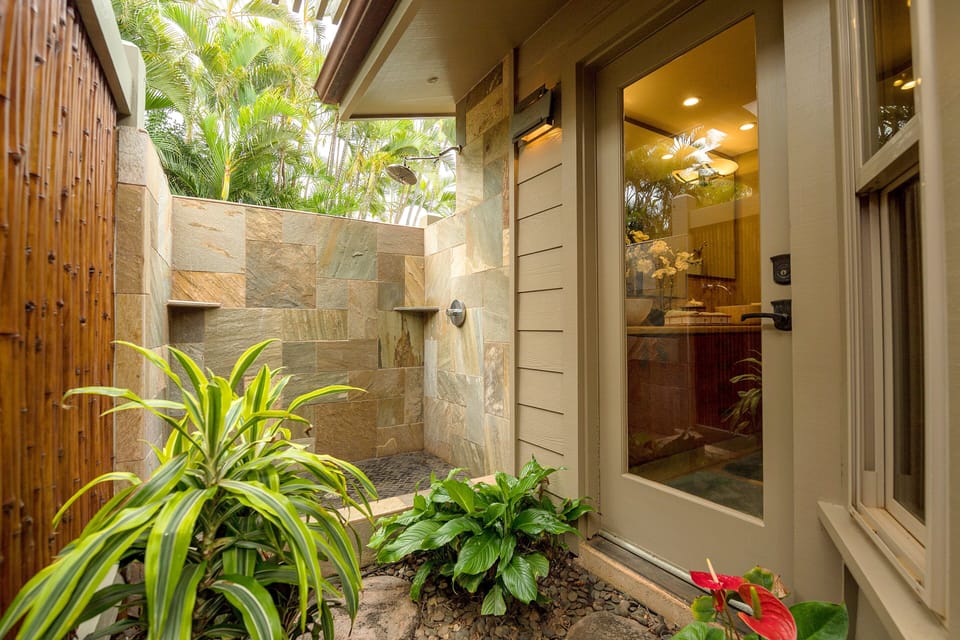 Experience ultimate privacy and relaxation with this beautifully designed outdoor shower, surrounded by lush tropical plants and bamboo accents.
