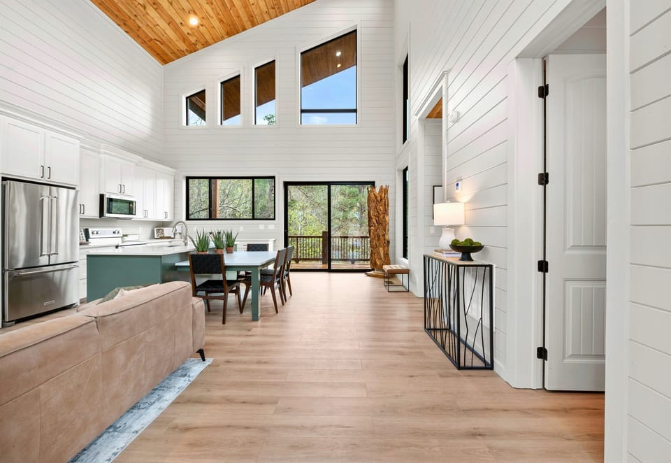 Tall windows and vaulted ceilings flood the open living area with natural light, making the space feel airy and welcoming.