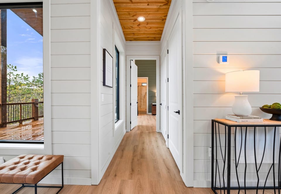 A bright, stylish hallway with hardwood floors and soft lighting guides you to the private bedrooms and cozy loft.