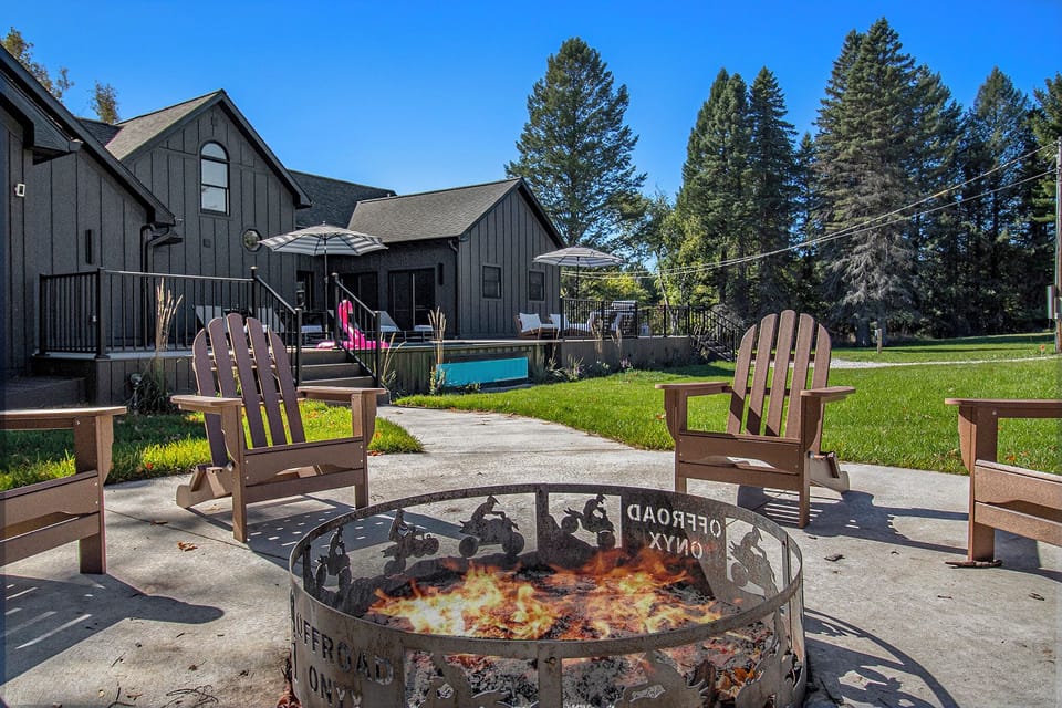 Relax by the custom fire pit at Offroad Onyx, perfect for cozy evenings under the stars. Enjoy a view of the modern outdoor pool and deck, complete with sun loungers and umbrellas, offering the ideal setting for both fun and relaxation.