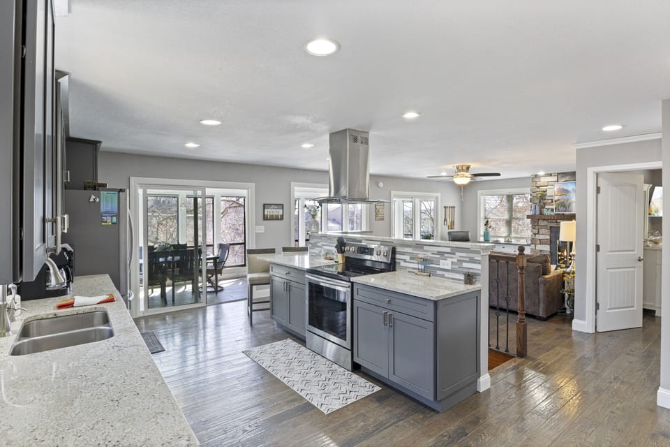 Modern kitchen with granite countertops, sleek appliances, and an open floor plan leading to the living area and patio.