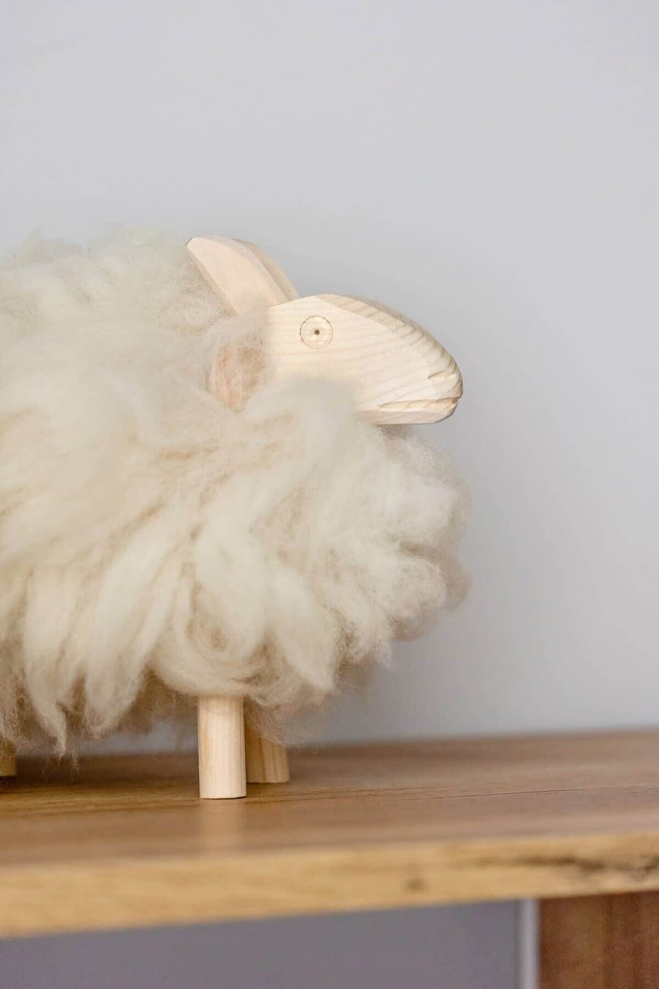 An adorable wooden sheep with soft woolly fur stands on a wooden shelf, adding warmth and cosiness to the interior.