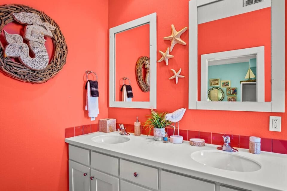 Fun coral bathroom with dual sinks, starfish details, and a splash of whimsy for your beach stay.
