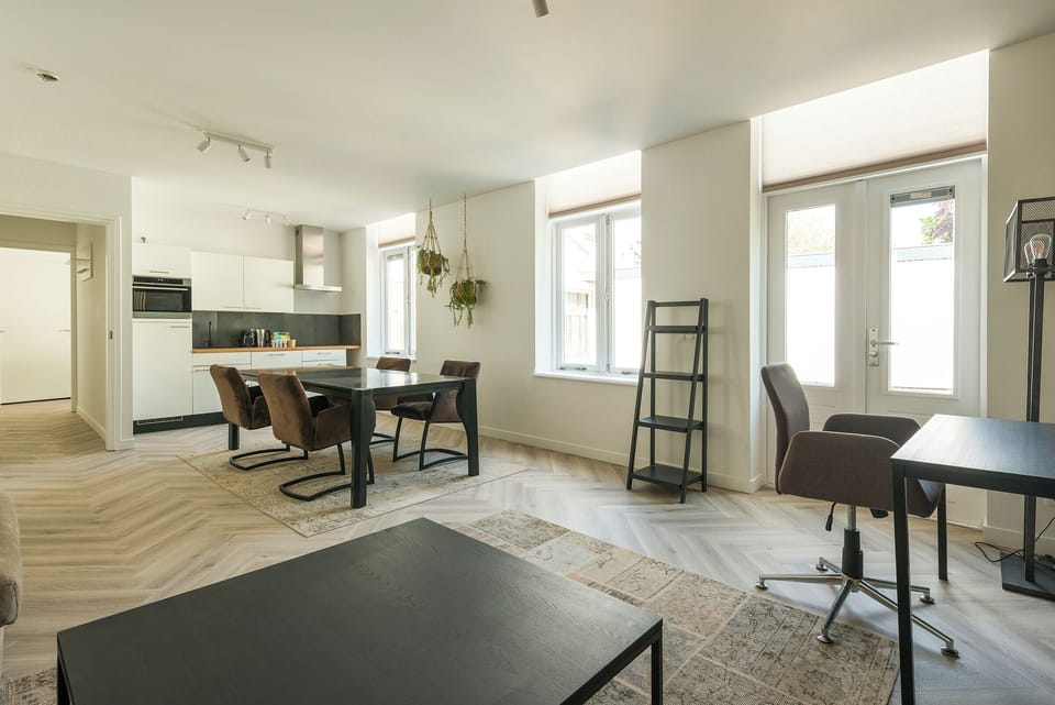 A seamless blend of living and dining areas with natural light streaming in through large windows, creating a warm and modern ambiance.