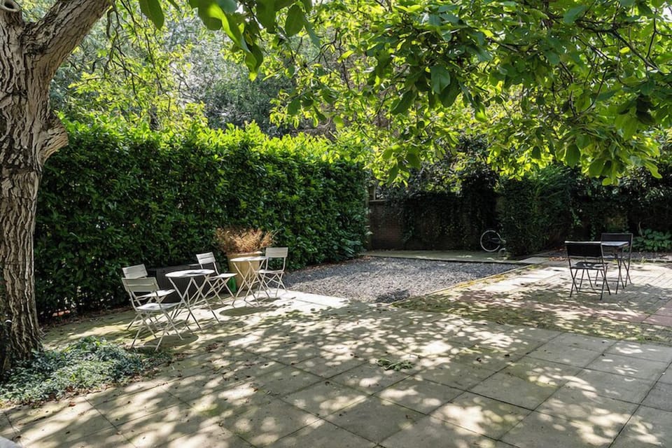 Serene outdoor patio area shaded by trees, providing a relaxing spot for guests to enjoy the fresh air and peaceful surroundings.