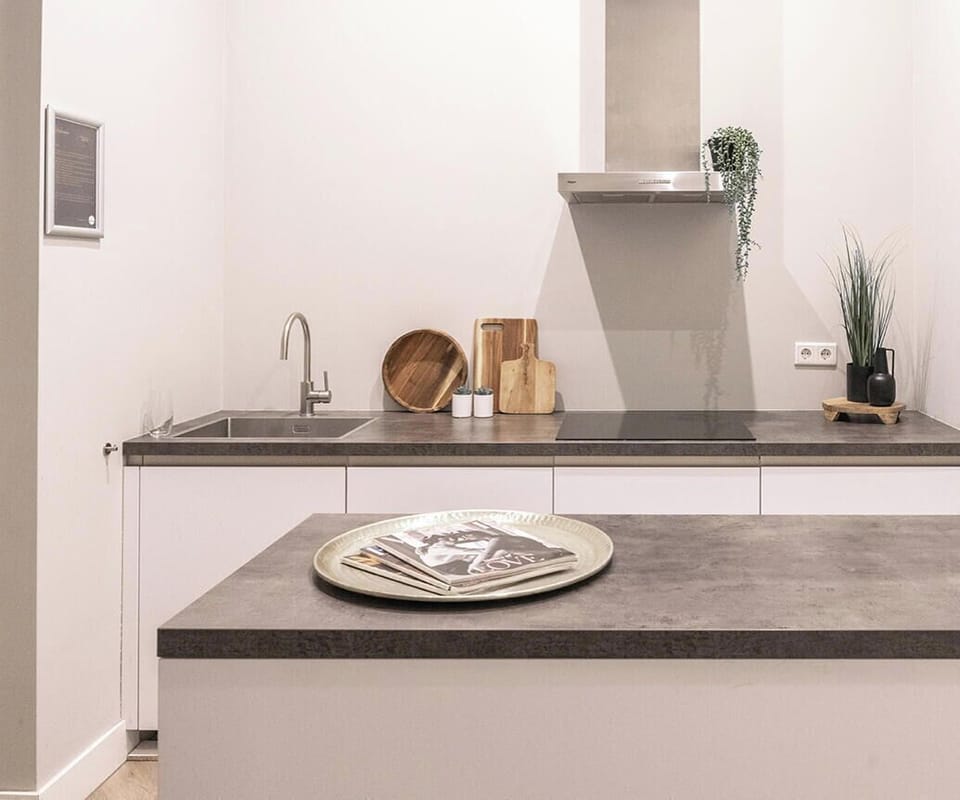 Gedeelde keukenruimte met een strak, modern design en functionele werkbladen, die een stijlvolle omgeving biedt voor het bereiden van maaltijden.