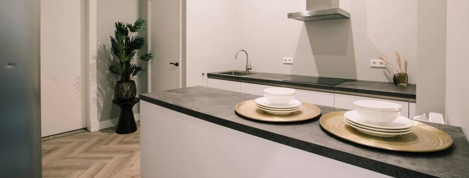 Shared with 2 otheA sleek shared kitchen with a modern design, featuring a black countertop, stainless steel range hood, elegant dishware, and tasteful decor for convenience and style.r suites