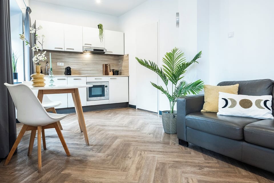 Enjoy a spacious living area with a comfortable sofa, chic pillows, and a sleek kitchen, where plants bring nature inside, offering a cozy retreat after visiting Efteling or Safari Park Beekse Bergen.