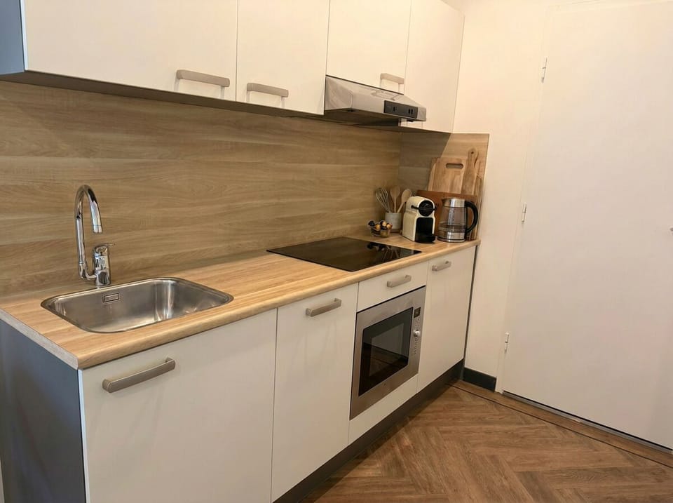 Modern kitchenette with stovetop, oven, coffee machine, and all essentials for preparing meals during your stay.