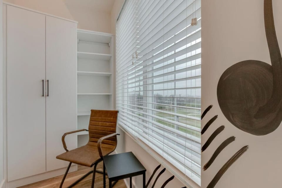 A bright room with a chair and wardrobe has a calm, organized feel for an easy stay.