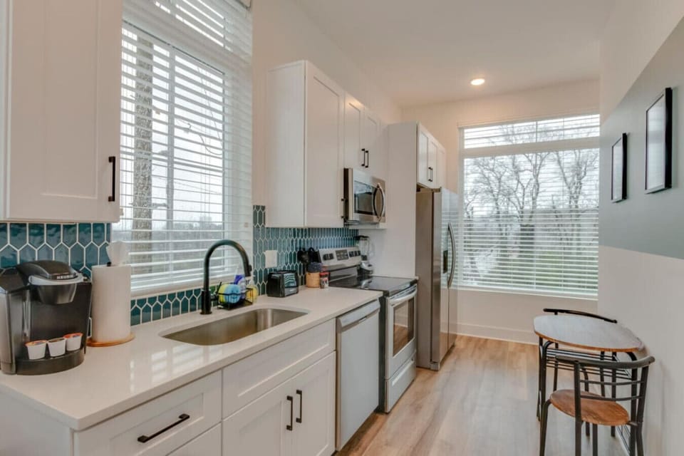 A bright kitchen with modern appliances, blue tile backsplash, and an open layout is ready for easy meals.