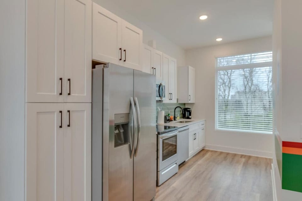 A clean kitchen with white cabinets and stainless appliances is stocked for easy home cooking.